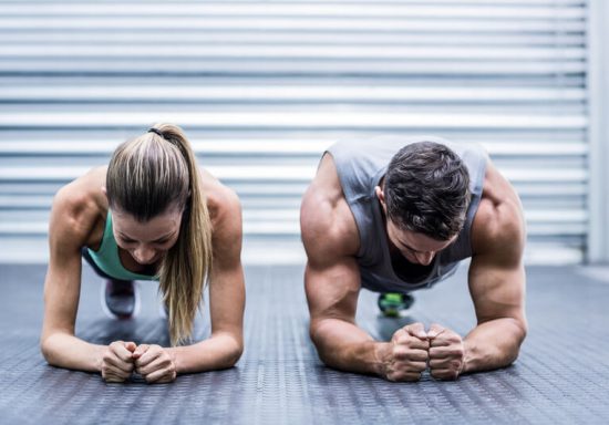Muscular couple doing planking exercises